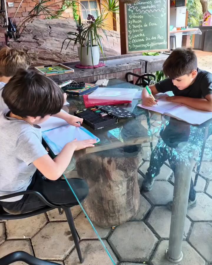 Crianças desenhando e fazendo atividades na mesa da varanda do Quintal