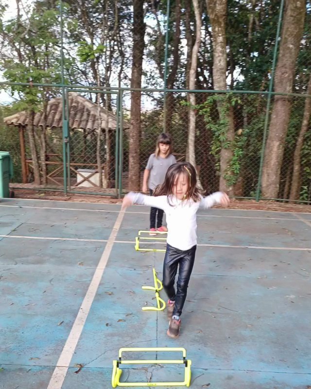 Menina fazendo circuito de iniciação esportiva na quadra